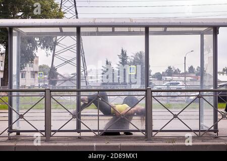 Femme avec briard se trouve sur le banc de l'arrêt des transports en commun. Banque D'Images