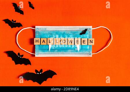 Lettering Halloween sur un masque de protection médicale sur fond noir avec silhouettes de chauves-souris en papier noir, Halloween 2020 dans une nouvelle réalité Banque D'Images