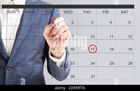 Les dates indiquées par un marqueur rouge sur le disque virtuel ne sont pas reconnaissables à la main d'un homme d'affaires calendrier Banque D'Images