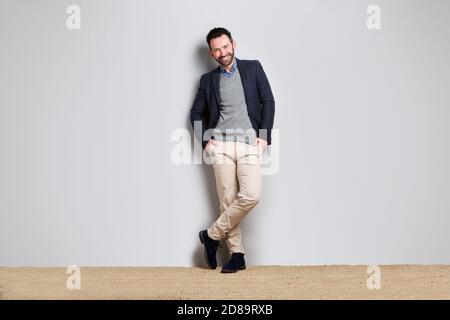 Portrait d'un homme d'affaires cool appuyé contre un mur gris Banque D'Images