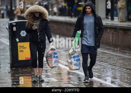 Les gens dehors et sur la pluie dans le Tier 3 Manchester. Banque D'Images