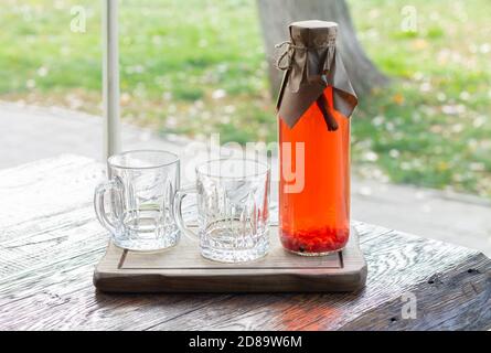Bouteille de grenat de thé épicé aux fruits avec tasses en verre table de pique-nique en bois Banque D'Images