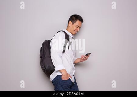 Portrait latéral d'un homme plus âgé détendu avec sac et mobile téléphone incliné vers un mur Banque D'Images