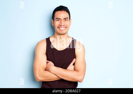 Portrait d'un homme asiatique d'âge moyen musclé portant un gilet debout avec confiance ses bras croisés sur fond bleu Banque D'Images