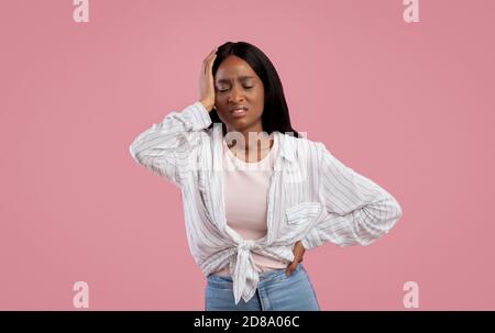 Femme noire surtravaillée souffrant de maux de tête sur fond rose studio, panorama Banque D'Images