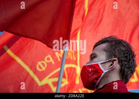 Moscou, Russie. 28 octobre 2020 UN partisan du parti communiste, portant un masque rouge avec l'écusson soviétique Komsomol, participe au rassemblement du Parti communiste sur la place Rouge pour marquer le 102e anniversaire de Komsomol, Ou encore la Ligue des jeunes communistes léninistes de toute l'Union, l'organisation de jeunesse communiste de l'époque soviétique, à Moscou, lors du roman coronavirus COVID-19 maladie en Russie Banque D'Images