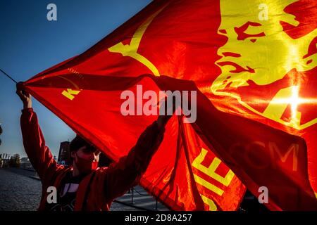 Moscou, Russie. 28 octobre 2020 UN partisan du parti communiste détient un drapeau rouge avec le badge Komsomol tandis que d'autres se rassemblent sur la place Rouge pour marquer le 102e anniversaire de Komsomol, ou la Ligue de jeunes communistes léninistes de toute l'Union, l'organisation de jeunesse communiste de l'ère soviétique, à Moscou, en Russie Banque D'Images