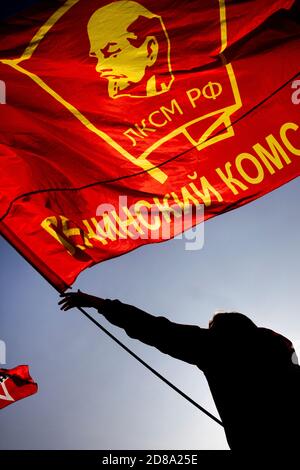 Moscou, Russie. 28 octobre 2020 UN partisan du parti communiste détient un drapeau rouge avec le badge Komsomol tandis que d'autres se rassemblent sur la place Rouge pour marquer le 102e anniversaire de Komsomol, ou la Ligue de jeunes communistes léninistes de toute l'Union, l'organisation de jeunesse communiste de l'ère soviétique, à Moscou, en Russie Banque D'Images