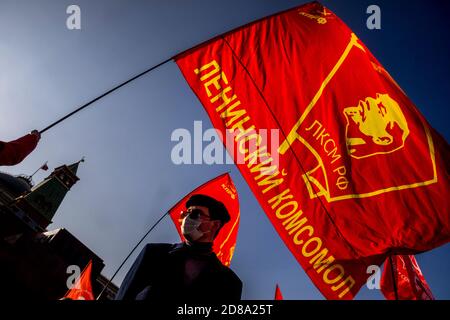 Moscou, Russie. 28 octobre 2020 UN partisan du parti communiste détient un drapeau rouge avec le badge Komsomol tandis que d'autres se rassemblent sur la place Rouge pour marquer le 102e anniversaire de Komsomol, ou la Ligue de jeunes communistes léninistes de toute l'Union, l'organisation de jeunesse communiste de l'ère soviétique, à Moscou, en Russie Banque D'Images