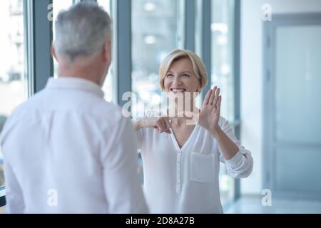 Femme blonde ayant une conversation avec un homme aux cheveux gris utilisant le langage des signes Banque D'Images