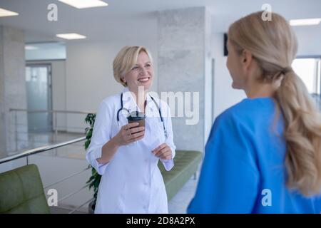 Deux femmes médecins appréciant le café, ayant une conversation amicale Banque D'Images