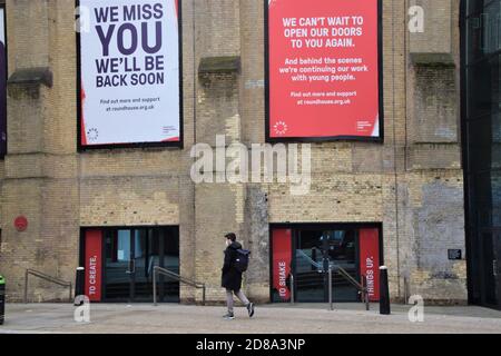 Un homme avec un masque passe devant le Roundhouse, la musique live et le centre artistique de Camden, Londres Banque D'Images