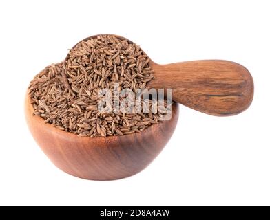 Graines de cumin dans un bol et une cuillère en bois, isolées sur fond blanc. Graines de cumin ou carvi. Banque D'Images