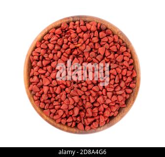 Graines d'annatto dans un bol en bois, isolées sur fond blanc. Graines d'achiote, bixa orellana. Colorant naturel pour la cuisine et la nourriture. Vue de dessus. Banque D'Images