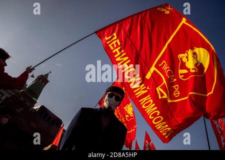 Moscou, Russie. 28 octobre 2020 UN partisan du parti communiste détient un drapeau rouge avec le badge Komsomol tandis que d'autres se rassemblent sur la place Rouge pour marquer le 102e anniversaire de Komsomol, ou la Ligue de jeunes communistes léninistes de toute l'Union, l'organisation de jeunesse communiste de l'ère soviétique, à Moscou, en Russie Banque D'Images