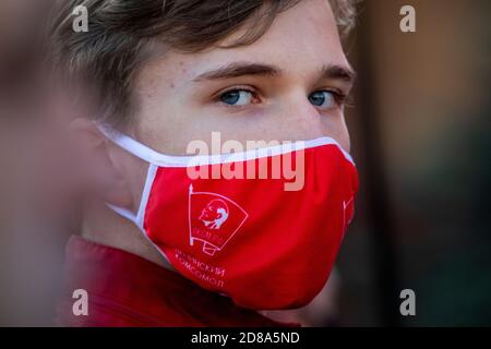 Moscou, Russie. 28 octobre 2020 UN partisan du parti communiste, portant un masque rouge avec l'écusson soviétique Komsomol, participe au rassemblement du Parti communiste sur la place Rouge pour marquer le 102e anniversaire de Komsomol, Ou encore la Ligue des jeunes communistes léninistes de toute l'Union, l'organisation de jeunesse communiste de l'époque soviétique, à Moscou, lors du roman coronavirus COVID-19 maladie en Russie Banque D'Images