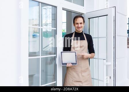 Jeune homme propriétaire utilisant une tablette numérique en magasin Banque D'Images