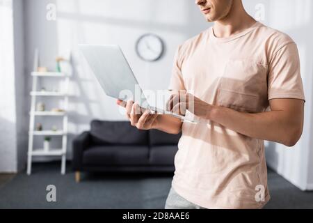 Vue rognée de l'homme utilisant un ordinateur portable à la maison, gagnant le concept en ligne Banque D'Images
