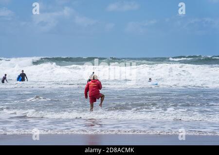Bude, Cornwall Royaume-Uni juillet 6 2020. Le maître nageur se dirige vers la mer pour fournir les premiers soins au surfeur en naufrage Banque D'Images