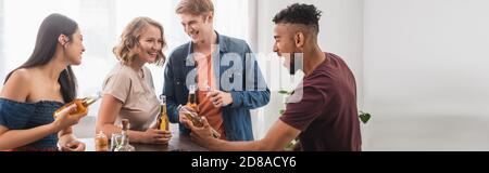 concept panoramique d'amis multiethniques avec des bouteilles de bière parlant pendant la fête Banque D'Images