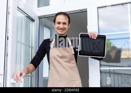 Jeune homme propriétaire utilisant une tablette numérique en magasin Banque D'Images