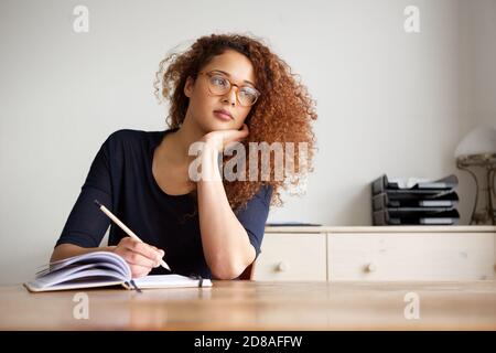 Portrait d'une étudiante assise au bureau et notes écrites dans le livre Banque D'Images