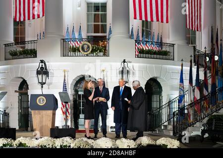 Le président Donald J. Trump regarde comme le juge associé de la Cour suprême des États-Unis Clarence Thomas jure dans la juge Amy Coney Barrett pour être le 115e juge associé de la Cour suprême lundi 23 octobre 2020, sur la pelouse sud de la Maison Blanche à Washington, Le juge Barrett est accompagné de son mari Jesse, qui tient la Bible, et de leurs enfants. (ÉTATS-UNIS) Banque D'Images