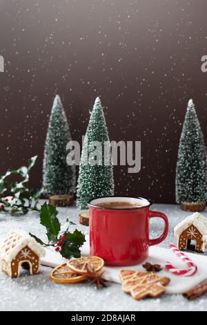 Cappuccino de Noël en tasse rouge sur table grise avec biscuits au pain d'épice et autres décorations de Noël. Carte de vœux de joyeux Noël. Banque D'Images