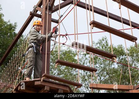 Jeune fille sur un cours de corde dans une aventure d'arbre stationner l'obstacle en passant les cordes de suspension Banque D'Images