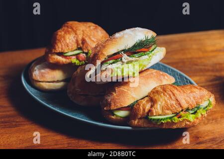 Assortiment de délicieux sandwichs à base de baguette, remplis de jambon en tranches fines ou salami et laitue verte fraîche ou basilic disposés dans un ligne oblique sur un ancien Banque D'Images