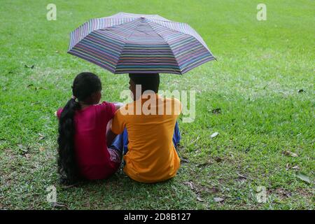 Kandy, Shri Lanka - 25 janvier 2013 : jardins botaniques royaux le jour des pluies. Couple homme et femme sous un parapluie marchant et appréciant le reste Banque D'Images