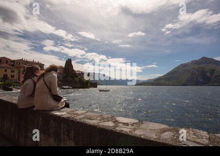 Deux femmes s'assoient sur un mur surplombant le lac de Côme, en Italie Banque D'Images