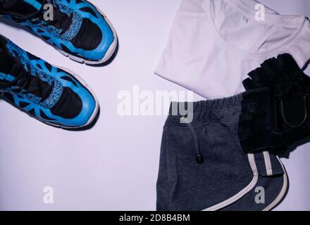 Vue de dessus des chaussures de training avec une tenue de sport pour femme et des gants d'entraînement sur une surface blanche Banque D'Images