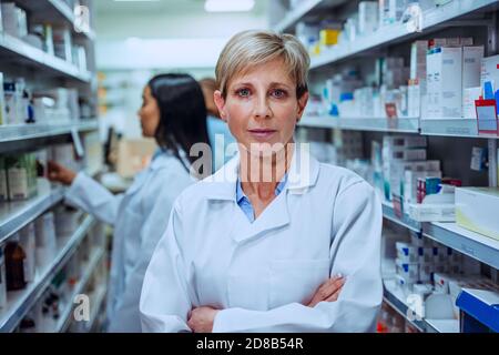 Femme chimiste debout avec des bras croisés portant un manteau de laboratoire blanc aspect dans l'île des médiations Banque D'Images