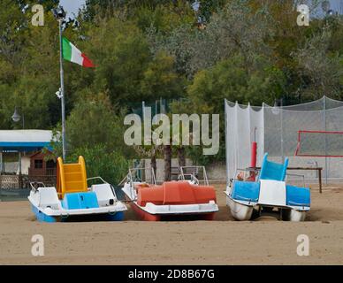 Trois bateaux à aubes avec drapeau italien sur une plage vide à Caorle, Venise, Italie, à la fin de la saison estivale. Banque D'Images