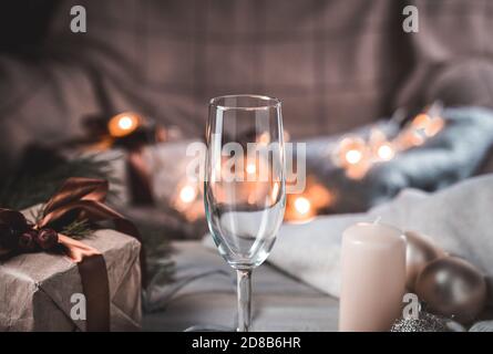 Coupe de champagne sur fond de Noël dans une ambiance chaleureuse le soir, avec des lanternes lumineuses en arrière-plan. Banque D'Images