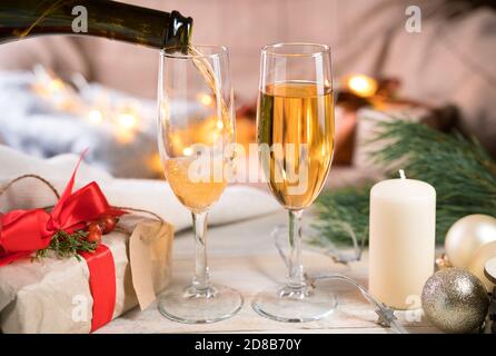 Deux verres et une bouteille de champagne, le processus de verser du champagne dans des verres dans la chambre dans une atmosphère chaleureuse. Banque D'Images