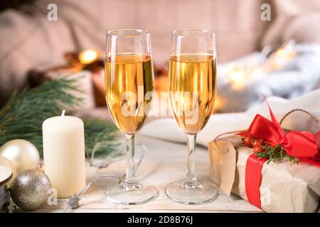 Deux verres de champagne, un cadeau et une bougie sur la table dans une atmosphère de Noël. Banque D'Images
