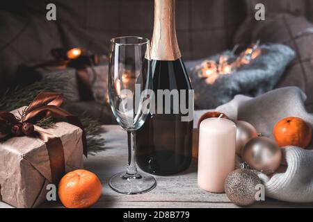 Une bouteille de champagne et un verre dans une atmosphère de Noël agréable le soir. Arrière-plan de vacances. Banque D'Images