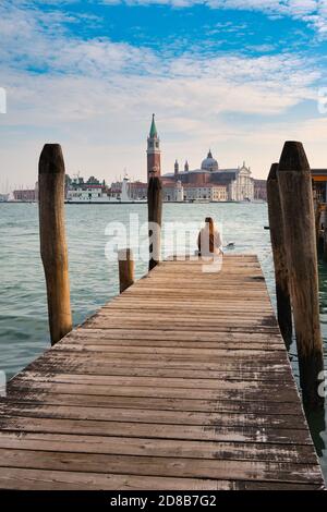 Vacances à Venise. Vue arrière de la belle fille appréciant la vue sur la lagune de Venise avec l'île de San Giorgio Maggiore et les gondoles Banque D'Images