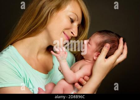 une jeune femme tient sa fille dans les bras. Photo de studio sur fond noir. Banque D'Images