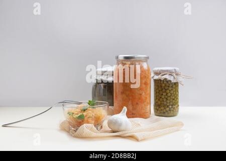 pots faits maison avec chou fermenté, petits pois, concombres marinés sur fond clair, un peu de choucroute dans un bol en verre Banque D'Images