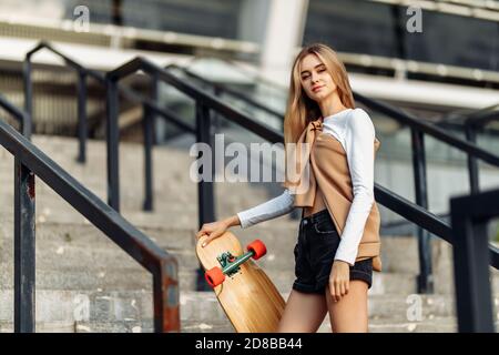 Belle blonde avec un skate dans ses mains. Banque D'Images