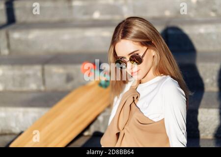 Belle blonde avec un skate dans ses mains. Banque D'Images