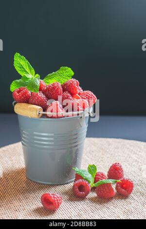 framboises mûres servies dans un seau gris sur fond gris comme dessert de saison sain Banque D'Images