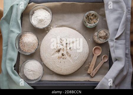 ingrédients pour faire cuire la pâte de levain maison: seigle, wholegrain, farine de blé simple, graines, entrée disposée sur papier de cuisson Banque D'Images