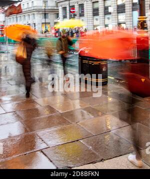 Les gens qui marchent sous la pluie le long de Piccadilly à l'extérieur du Ritz Et Green Park Underground à Londres avec parasols de couleur Banque D'Images