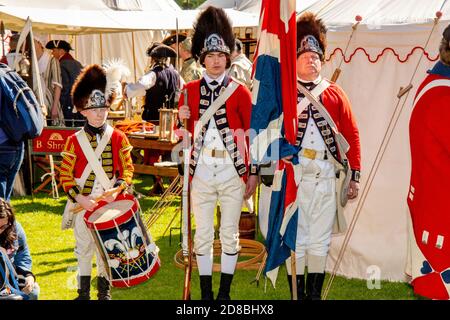 Les soldats de l'armée britannique Redcoat et un garçon de batteur sont dépeints par des acteurs lors d'une reconstitution de la guerre d'indépendance américaine dans un Huntington Beach, CA. Banque D'Images