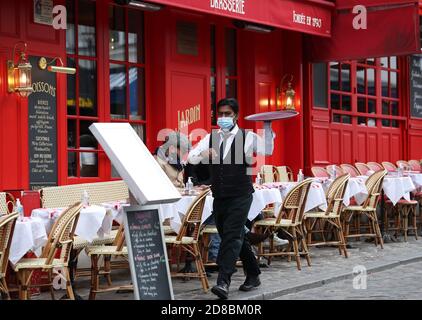 Paris, France. 28 octobre 2020. Un serveur sert sur la terrasse d'un restaurant de la place du Tertre à Montmartre, Paris, France, 28 octobre 2020. La France va entrer dans le confinement national à partir de vendredi pour endiguer la deuxième vague de l'épidémie du coronavirus, a annoncé mercredi soir le président Emmanuel Macron. La France a enregistré mercredi 36,437 nouvelles infections à COVID-19, soit 3,020 de plus que le nombre enregistré dans les 24 heures précédentes. Credit: Xinhua/Alay Live News Banque D'Images