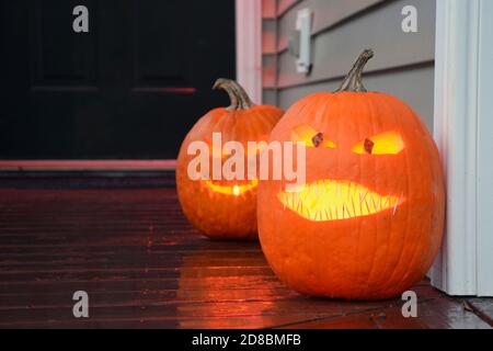 Des citrouilles sculptées brillent sur le porche avant d'une maison pendant l'Halloween. Banque D'Images